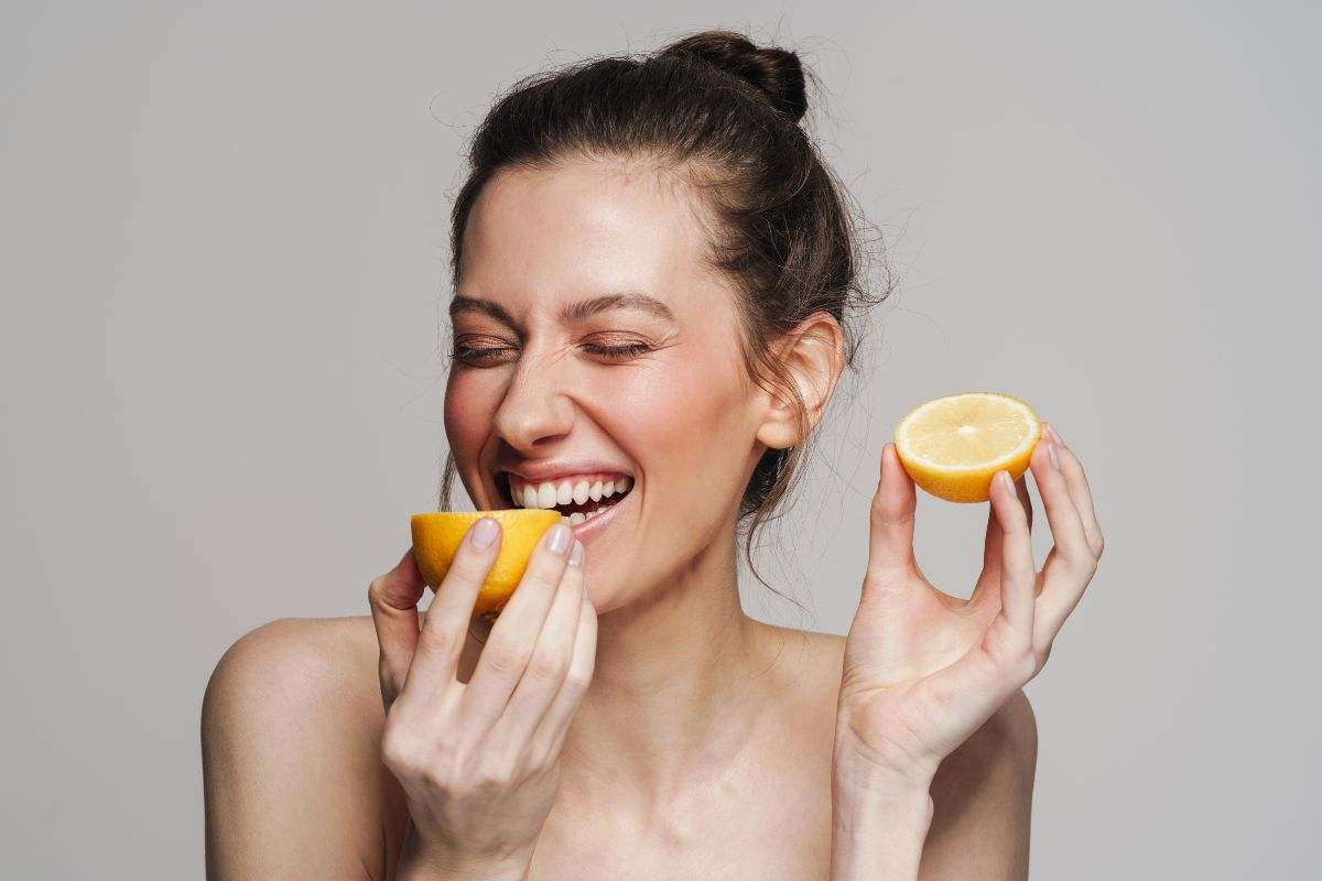 Ragazza sorridente addenta un limone